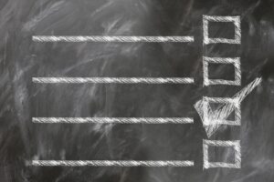 A chalkboard checklist with horizontal lines and a single box marked with a check.