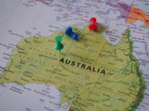 A printed map of Australia with colorful pushpins placed on different regions.