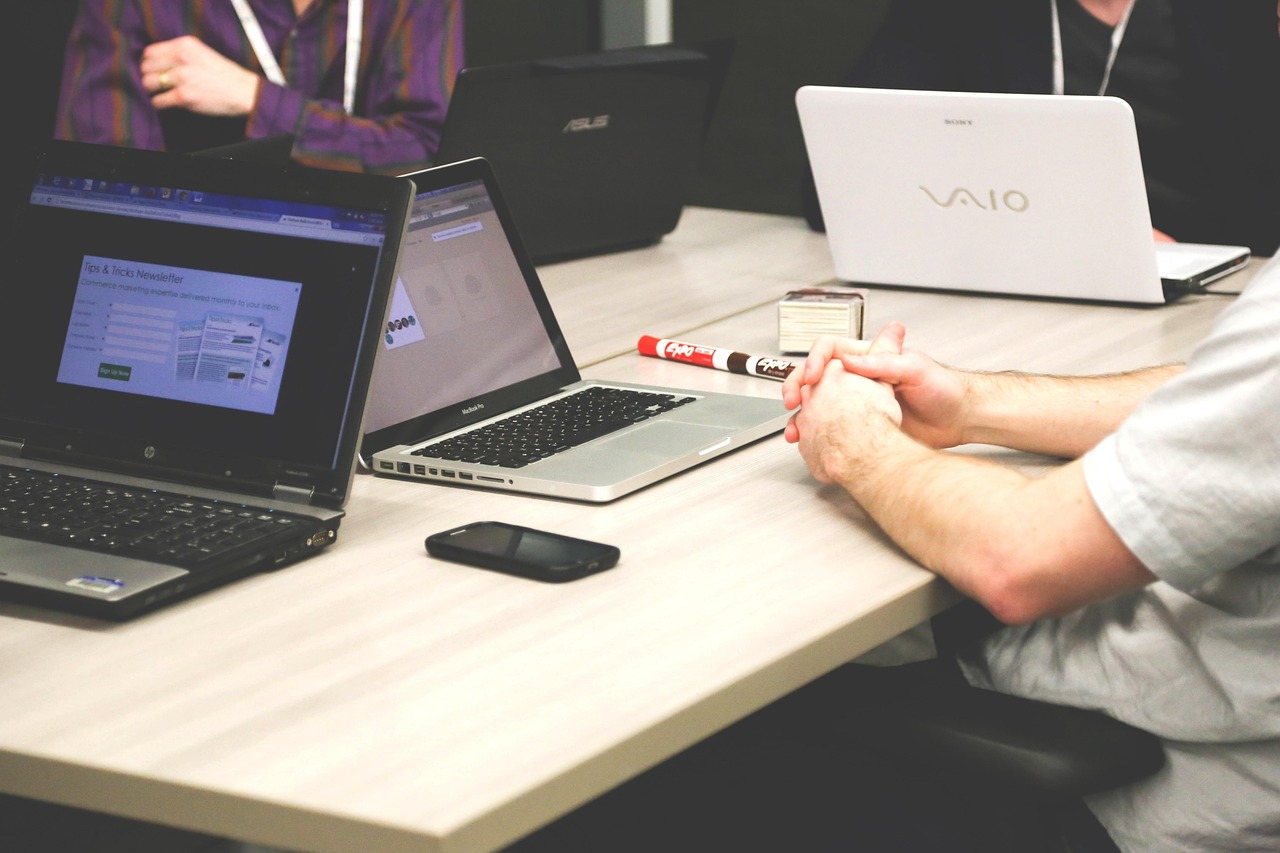 People sitting around a conference table with open laptops during a business meeting.